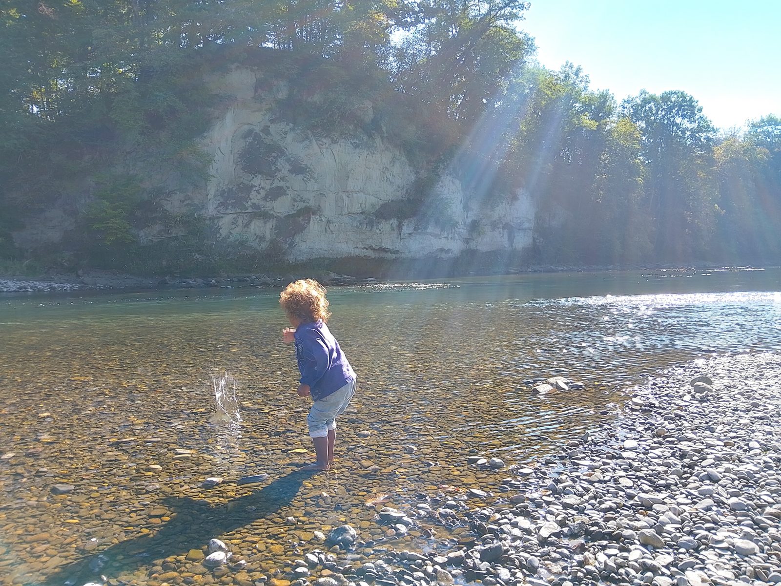 Ein Kind wirft einen Stein ins Wasser, es spritzt