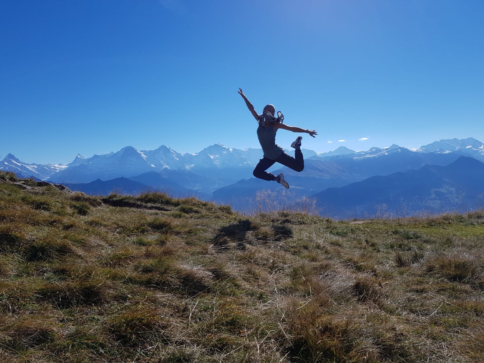 Miriam Emilia springt mit ausgebreiteten Armen vor dem Panorama der Berner Alpen